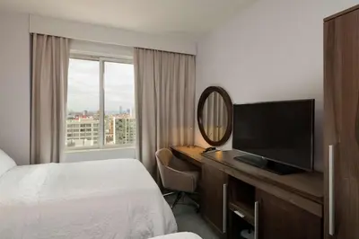 a hotel room with a bed and a desk with a mirror at Hampton Inn Manhattan - Times Square South in New York