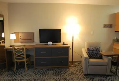 a hotel room with a desk with a television and a chair at Candlewood Suites Harrisburg I-81 Hershey Area by IHG in Harrisburg
