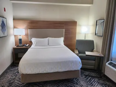 a hotel room with a bed and a chair at Candlewood Suites Harrisburg I-81 Hershey Area by IHG in Harrisburg