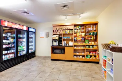 a grocery store aisle with a refrigerator and food at Candlewood Suites Harrisburg I-81 Hershey Area by IHG in Harrisburg