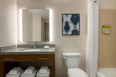 a bathroom with a toilet and a sink and a mirror at Candlewood Suites Harrisburg I-81 Hershey Area by IHG in Harrisburg