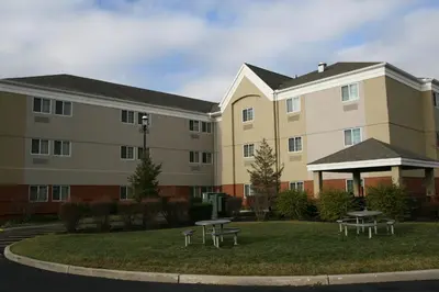 a large building with two picnic tables in front of it at Candlewood Suites Bordentown-Trenton by IHG in Bordentown