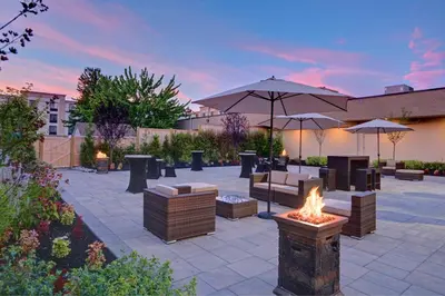 a patio with a fire pit and tables and umbrellas at Holiday Inn East Windsor by IHG in Hightstown