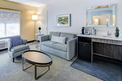 a living room with a couch a chair and a table at Holiday Inn East Windsor by IHG in Hightstown