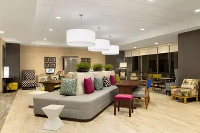 a lobby with a couch and a table and chairs at Home2 Suites By Hilton Hasbrouck Heights in Hasbrouck Heights