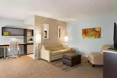 a living room with a couch a chair and a desk at Home2 Suites By Hilton Hasbrouck Heights in Hasbrouck Heights