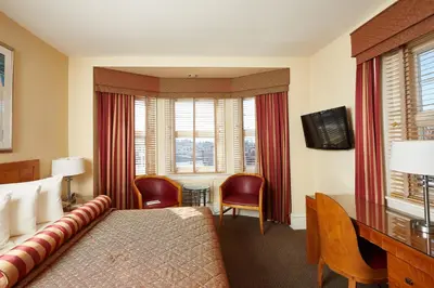 a hotel room with a bed and a desk and windows at Alexander Inn in Philadelphia