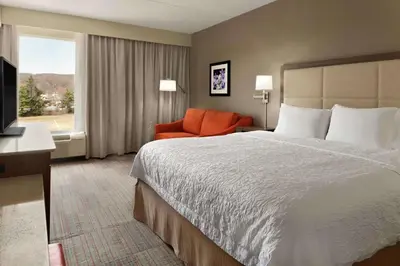 a hotel room with a bed and a chair and a window at Hampton Inn Denville-Rockaway-Parsippany in Denville