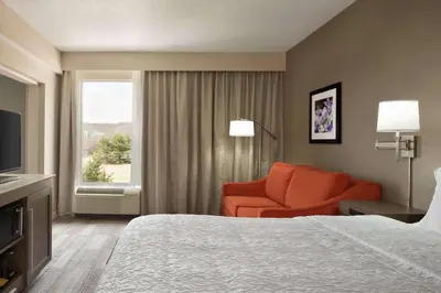 a hotel room with a bed and a chair and a window at Hampton Inn Denville-Rockaway-Parsippany in Denville