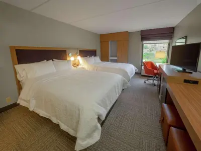a hotel room with two beds and a flat screen tv at Hampton Inn Hazleton in Hazleton