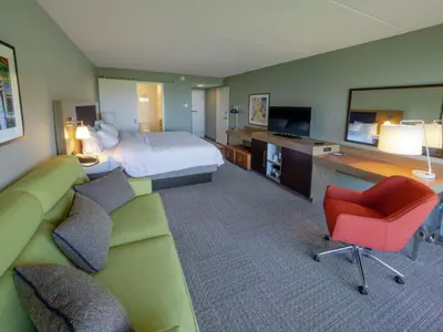 a hotel room with a bed and a couch and a television at Hampton Inn Hazleton in Hazleton