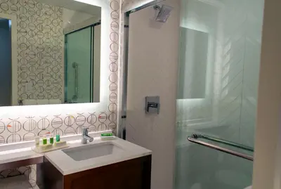 a bathroom with a sink and a shower with a mirror at Holiday Inn Binghamton-Downtown Hawley Street by IHG in Binghamton