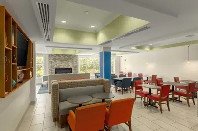 a restaurant with tables and chairs and a fireplace at Holiday Inn Express Hotel & Suites Binghamton University-Vestal by IHG in Vestal