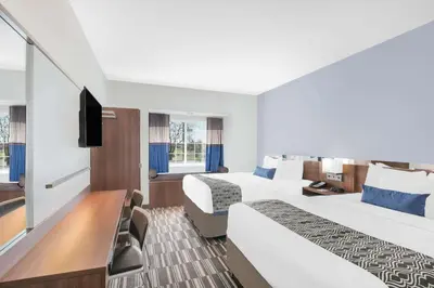 a hotel room with two beds and a flat screen tv at Microtel Inn & Suites by Wyndham Binghamton in Binghamton