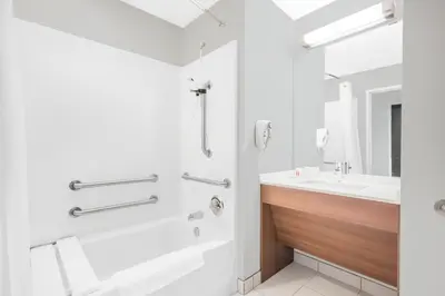 a white bathroom with a tub and a sink at Microtel Inn & Suites by Wyndham Binghamton in Binghamton