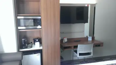 a small kitchen with a desk and a microwave at Microtel Inn & Suites by Wyndham Binghamton in Binghamton