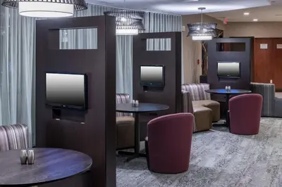 a waiting room with tables and chairs and televisions at Courtyard by Marriott West Orange in West Orange