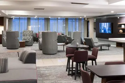 a lobby with tables and chairs and a flat screen tv at Courtyard by Marriott West Orange in West Orange