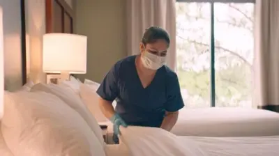 a man in a mask making a bed at Bluegreen Vacations Suites at Hershey in Hershey
