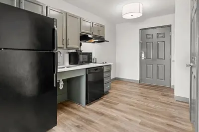 a kitchen with a black refrigerator and wooden floors at Candlewood Suites Hazleton by IHG in Hazleton