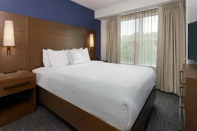 a bedroom with a large bed and a large window at Residence Inn Wayne in Wayne