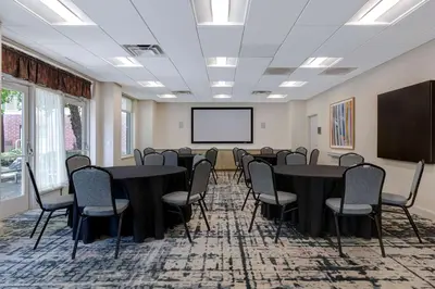 a conference room with tables and chairs and a screen at Homewood Suites Lansdale in Lansdale