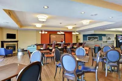 a dining room with tables and chairs and a fireplace at Hampton Inn Scranton at Montage Mountain in Scranton