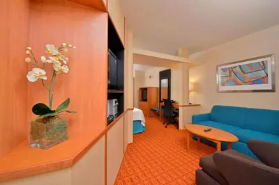 a living room with a blue couch and a table at Fairfield Inn and Suites by Marriott Williamsport in Williamsport
