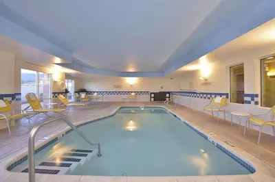 a large pool in a hotel with chairs and tables at Fairfield Inn and Suites by Marriott Williamsport in Williamsport