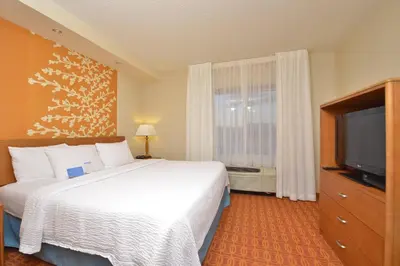 a hotel room with a bed and a flat screen tv at Fairfield Inn and Suites by Marriott Williamsport in Williamsport
