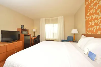a hotel room with a bed and a flat screen tv at Fairfield Inn and Suites by Marriott Williamsport in Williamsport
