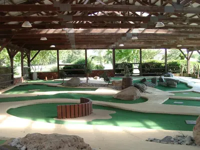 a golf course with rocks and trees in a building at Circle M Camping Resort Loft Park Model in Wabank