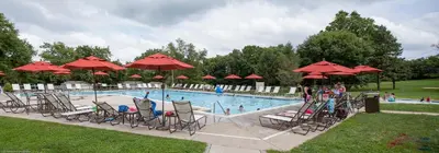 a swimming pool with chairs and red umbrellas at Circle M Camping Resort Loft Park Model in Wabank