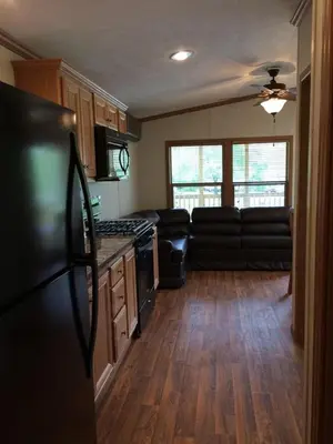 a kitchen with a black refrigerator and a couch at Circle M Camping Resort Screened Park Model in Wabank