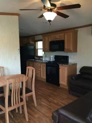 a living room with a table and a kitchen at Circle M Camping Resort Screened Park Model in Wabank