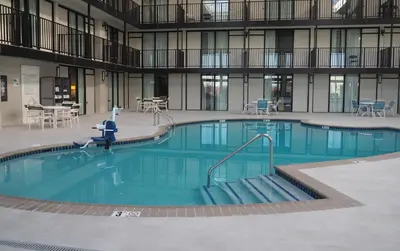 a large pool in a building with tables and chairs at Holiday Inn Harrisburg I-81 Hershey Area by IHG in Grantville