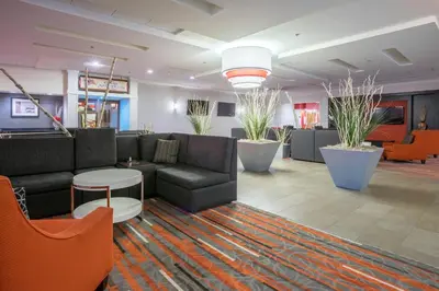 a lobby with couches and tables and plants at Holiday Inn Harrisburg I-81 Hershey Area by IHG in Grantville