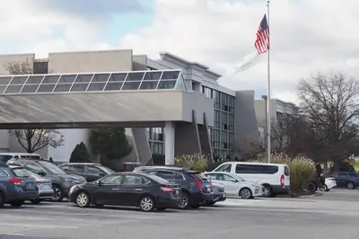 a group of cars parked in front of a building with an american flag at Holiday Inn Harrisburg I-81 Hershey Area by IHG in Grantville