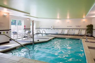 a swimming pool with chairs and tables in a building at Fairfield Inn & Suites Lock Haven in Lock Haven