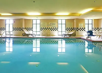 a pool in a hotel with chairs and tables at Hampton Inn North Brunswick NJ in North Brunswick