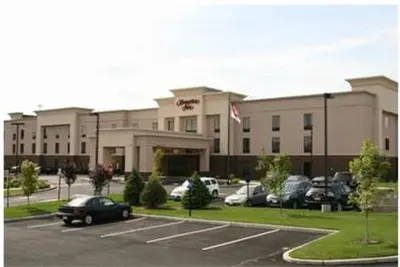 a large building with cars parked in a parking lot at Hampton Inn North Brunswick NJ in North Brunswick