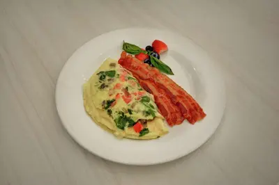 a white plate of food with omelet and vegetables on a table at Hilton Garden Inn Ridgefield Park in Ridgefield Park