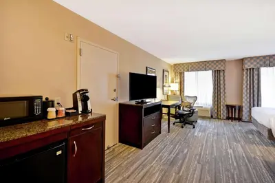 a hotel room with a bed and a desk with a television at Hilton Garden Inn Ridgefield Park in Ridgefield Park