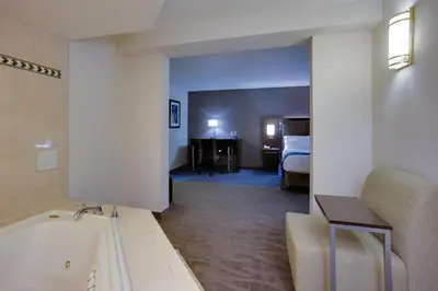 a hotel room with a bath tub and a bedroom at Holiday Inn Express Hotel & Suites Meadowlands Area by IHG in Carlstadt