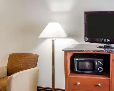 a room with a lamp and a tv and a chair at Hotel Hanna in Harrisburg