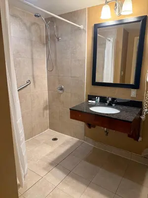 a bathroom with a sink and a shower with a mirror at Hotel Hanna in Harrisburg