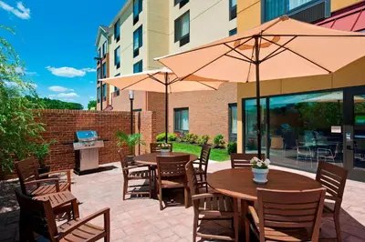 an outdoor patio with tables and chairs with umbrellas at TownePlace Suites by Marriott Bethlehem Easton/Lehigh Valley in Hollo