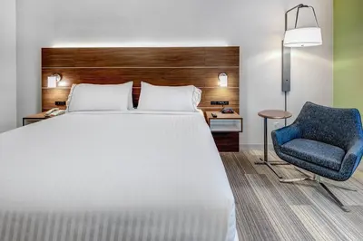 a bedroom with a bed and a blue chair at Holiday Inn Express Woodbridge by IHG in Avenel