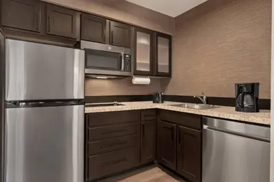 a kitchen with brown cabinets and a stainless steel refrigerator at Residence Inn Deptford in Almonesson