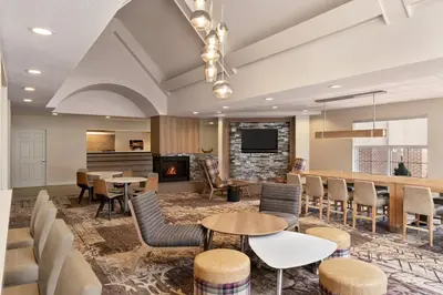 a lobby with tables and chairs and a fireplace at Residence Inn Deptford in Almonesson